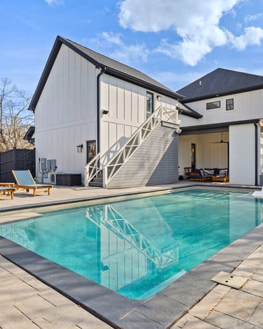 Modern farmhouse with swimming pool, lounge chairs, pergola, and basketball hoop in backyard